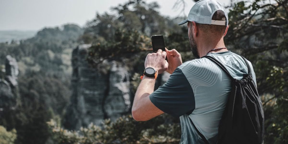 A man captures the beauty of Czech nature with his smartphone while hiking outdoors.
