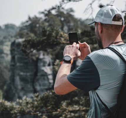 A man captures the beauty of Czech nature with his smartphone while hiking outdoors.