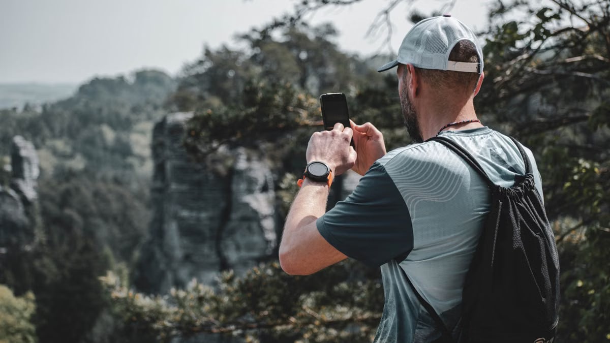 A man captures the beauty of Czech nature with his smartphone while hiking outdoors.